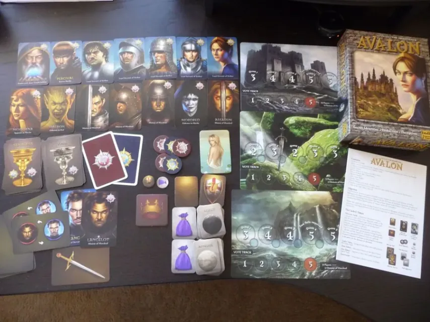 All Avalon components spread on a table: character cards, tableau, quest, team and vote tokens, and markers.