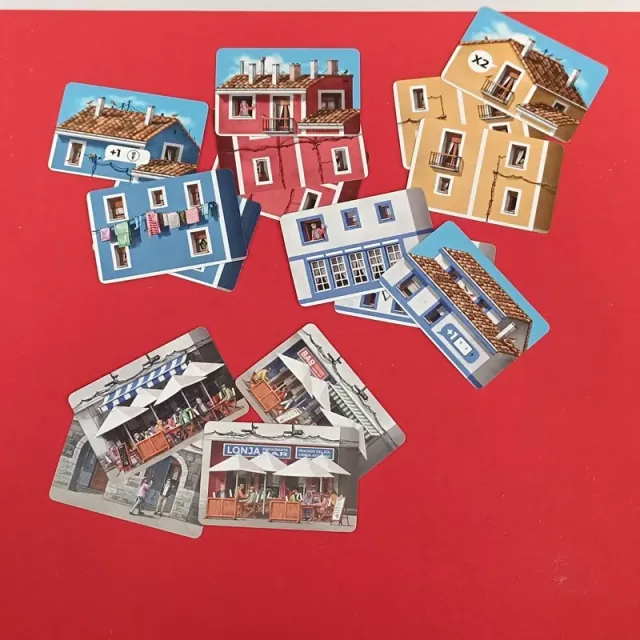 Cartas de portal con fachadas de bares y comercios, y cartas de tejado con tejados rojos y bonificaciones impresas.