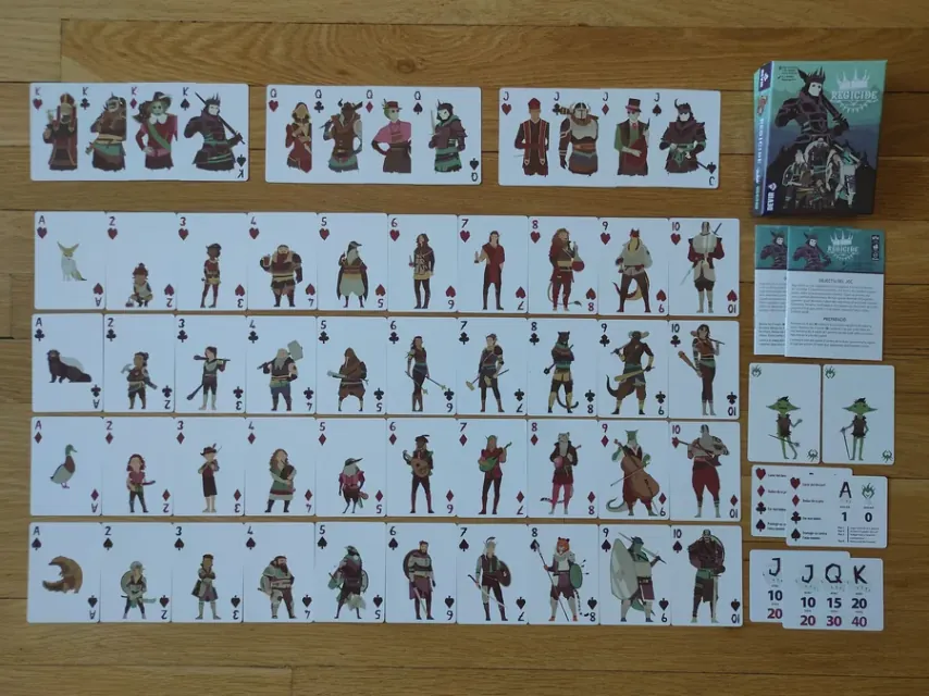 The full Regicide deck spread on a wooden table, with the number cards, the four animal aces and the face cards separated above.