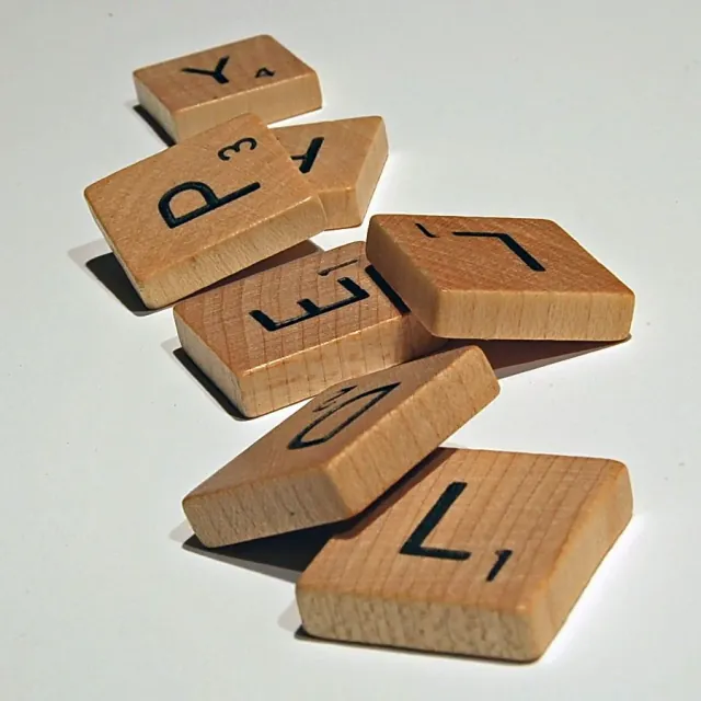 Fichas de Scrabble con letras y valores de puntos, entre ellas Y de 4 y L de 1.