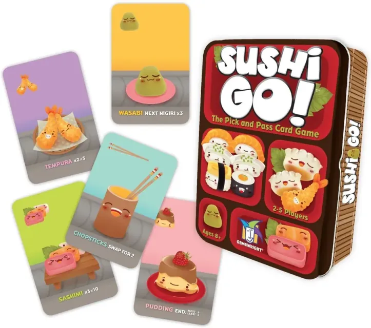 Caja de Sushi Go! junto a cartas de tempura, wasabi, palillos, sashimi y pudin sobre una mesa clara.